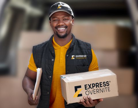 Male black delivery driver smiling holding packages.